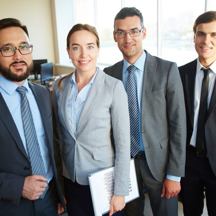 Group of business partners looking at camera with smiles in office